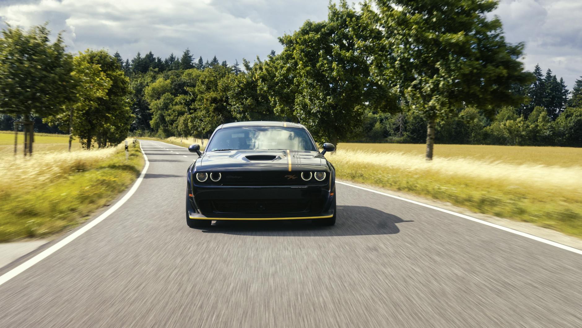 Sportowe auto jedzie krętą wiejską drogą wśród zielonych drzew