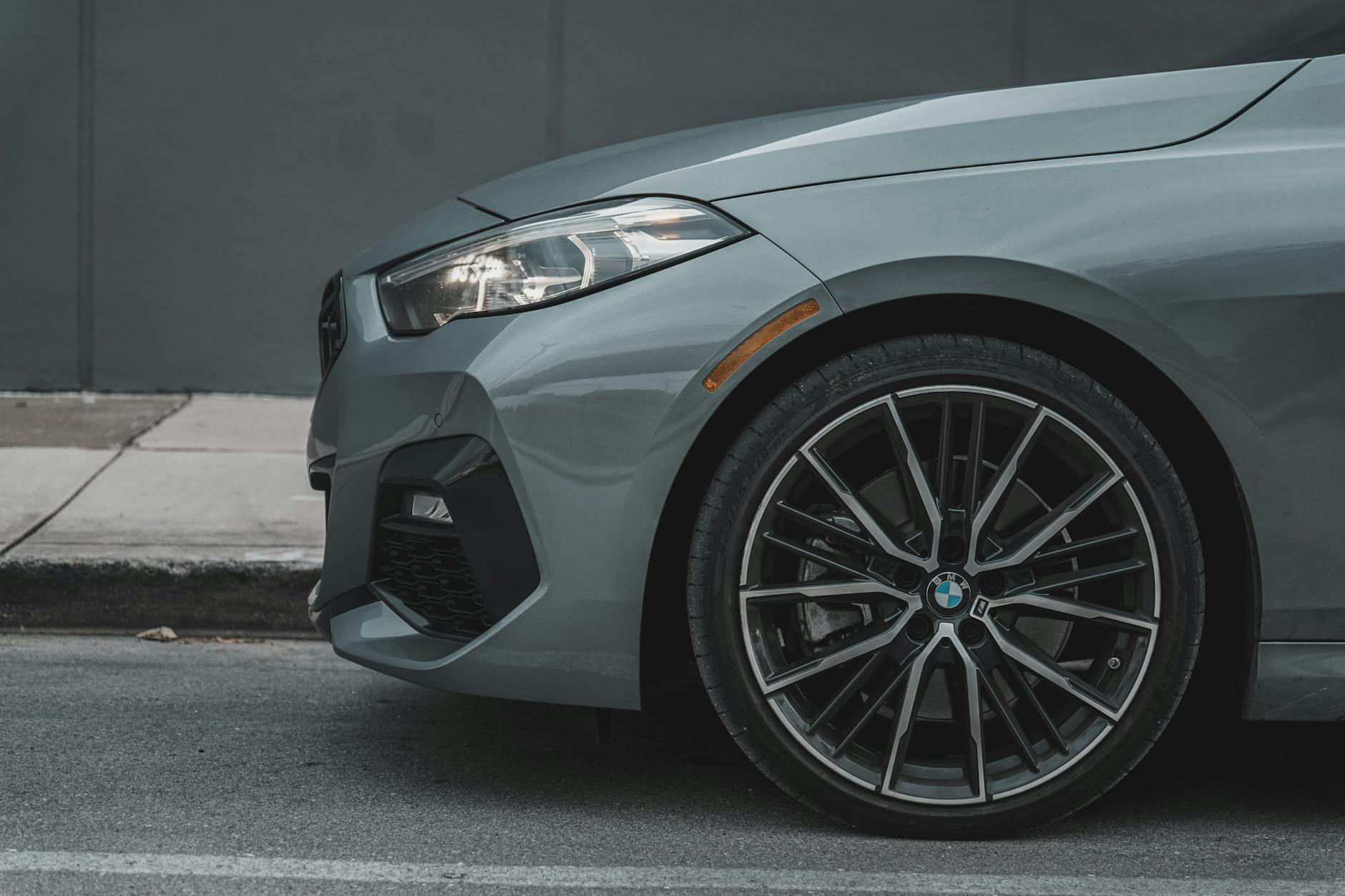 Przednie koło szarego auta zaparkowanego przy krawężniku w mieście