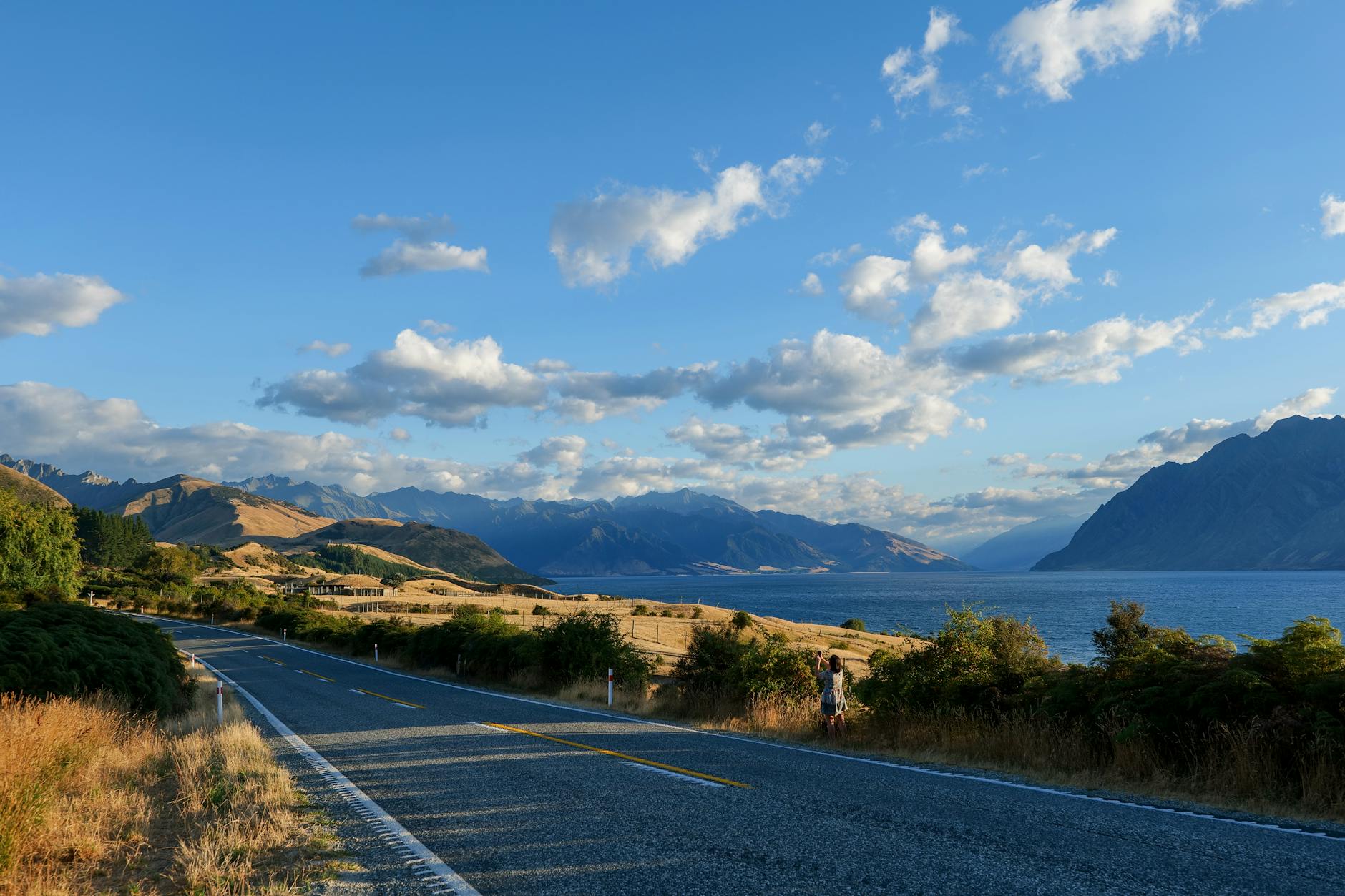 Samochód na drodze między jeziorem a górami na Wyspie Południowej
