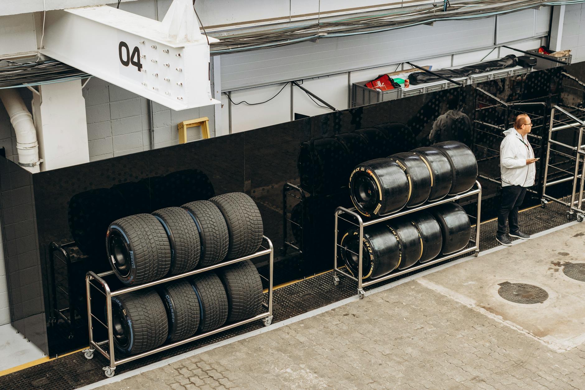 Stos opon wyścigowych w garażu serwisowym z mechanikiem obok