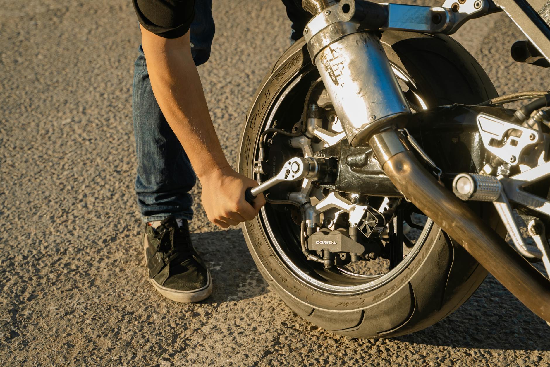 Dokręcanie koła motocykla kluczem po serwisie na zewnątrz