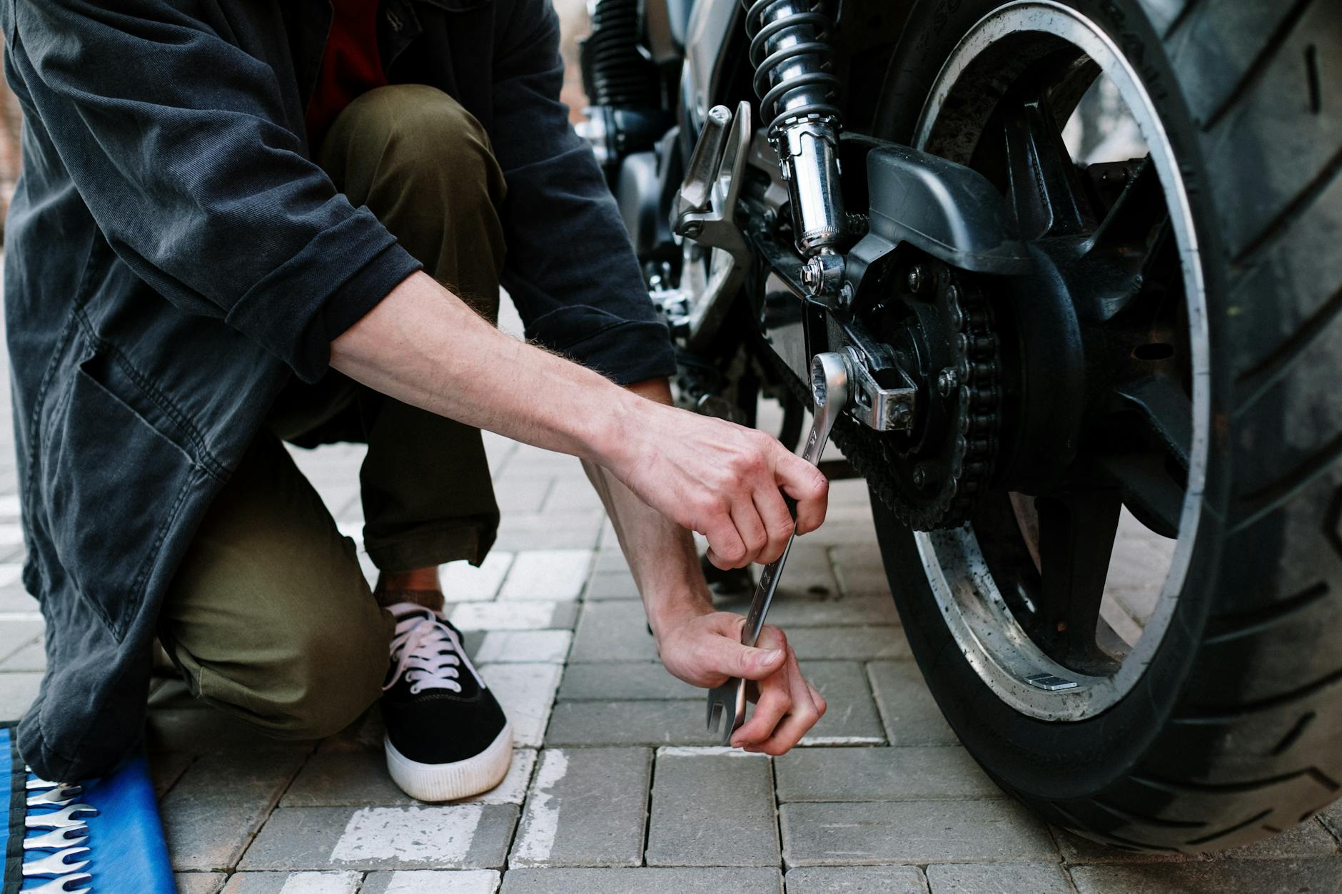 Mechanik na zewnątrz dokręca koło motocykla kluczem