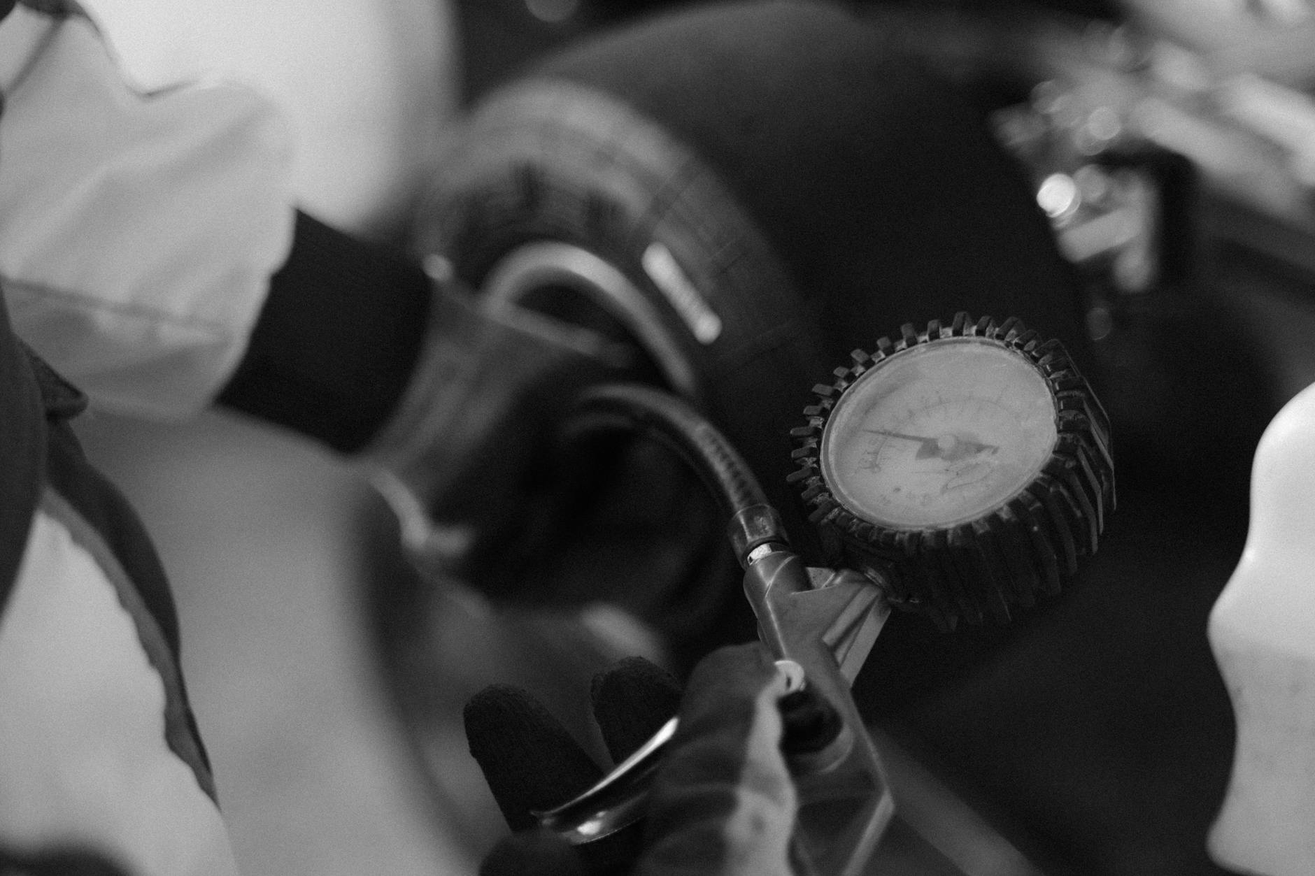 Mechanik sprawdza ciśnienie w oponie małego pojazdu miernikiem