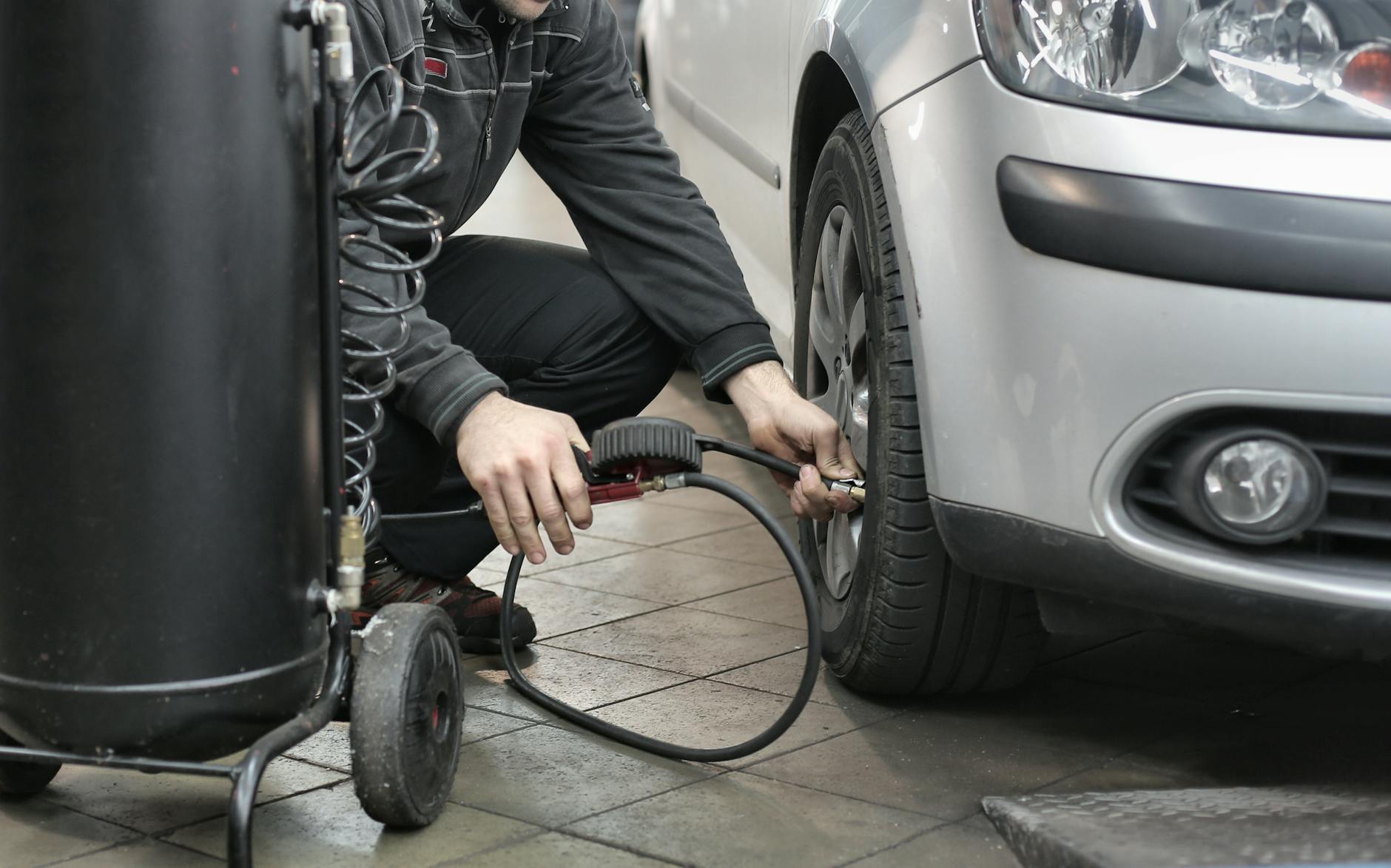 Mechanik sprawdza i reguluje ciśnienie w oponie samochodu w warsztacie