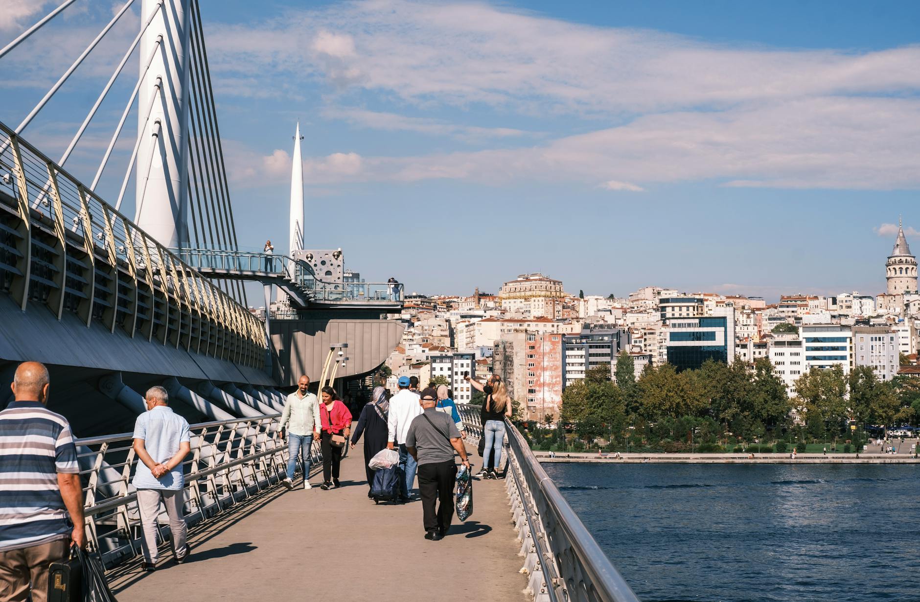Przechodnie na moście nad Złotym Rogiem z widokiem na wieżę Galata