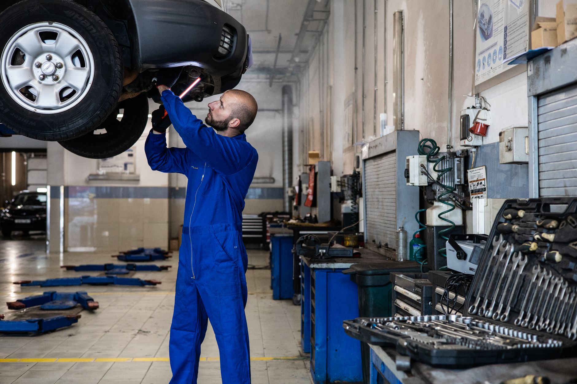 Mechanik sprawdza podniesioną Toyotę Corollę na podnośniku w warsztacie