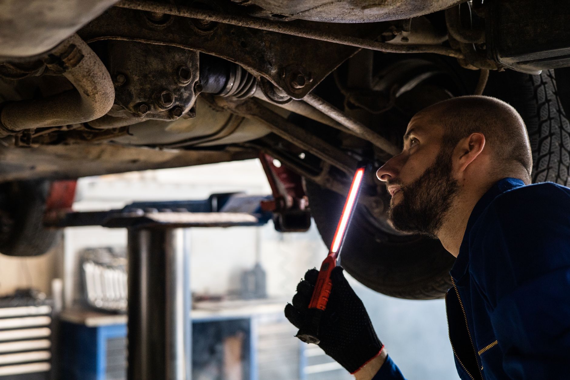 Mechanik z latarką sprawdza podwozie auta w warsztacie
