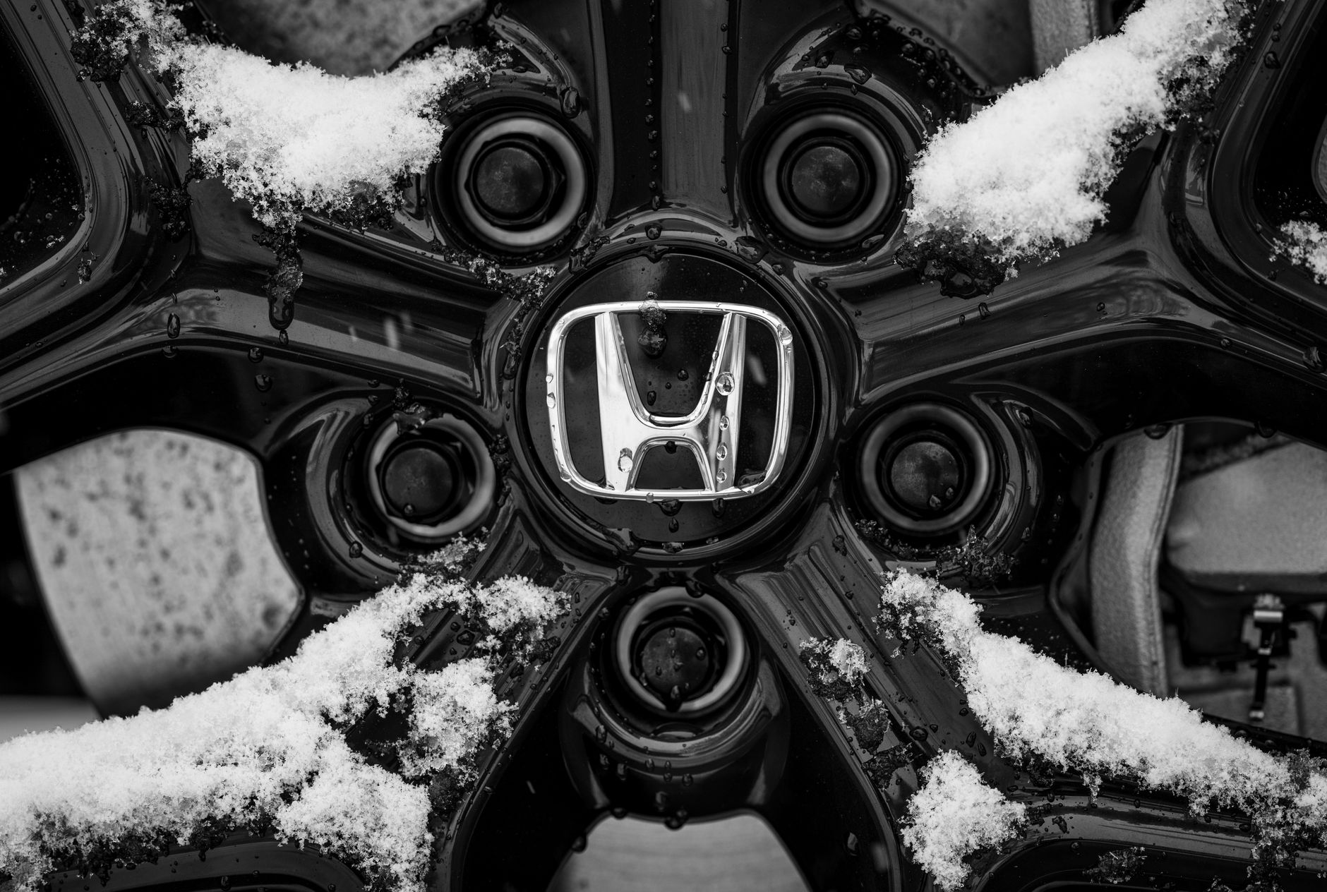 Czy malowanie proszkowe felg jest bezpieczne? Co sprawdzić przed i po Zbliżenie na ośnieżone logo Honda na feldze w zimowych warunkach